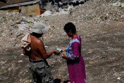 Indonesia ha lanzado un plan para reducir los desechos plásticos marinos en un 70% para 2025, prometiendo gastar $ 1 mil millones, pero no está claro cuánto progreso se ha hecho. En la imagen, Sunarni recibe dinero de un trabajador después de descargar basura en el pueblo de Bangun en Mojokerto, provincia de Java Oriental, Indonesia,