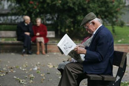 Un jubilado lee un peri&oacute;dico en un parque.