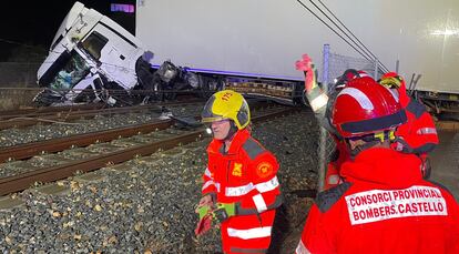 Los bomberos tratan de desalojar el camión volcado sobre las vías en las inmediaciones de la localidad castellonense de Nules.