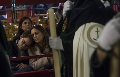 Entre la información ofrecida, se detalla que de forma previa a los incidentes se detuvo a una persona por desobediencia en la calle Pastor y Landero. En la imagen, una pareja descansa mientras los nazarenos de la Esperanza de Triana pasan por la Carrera Oficial.