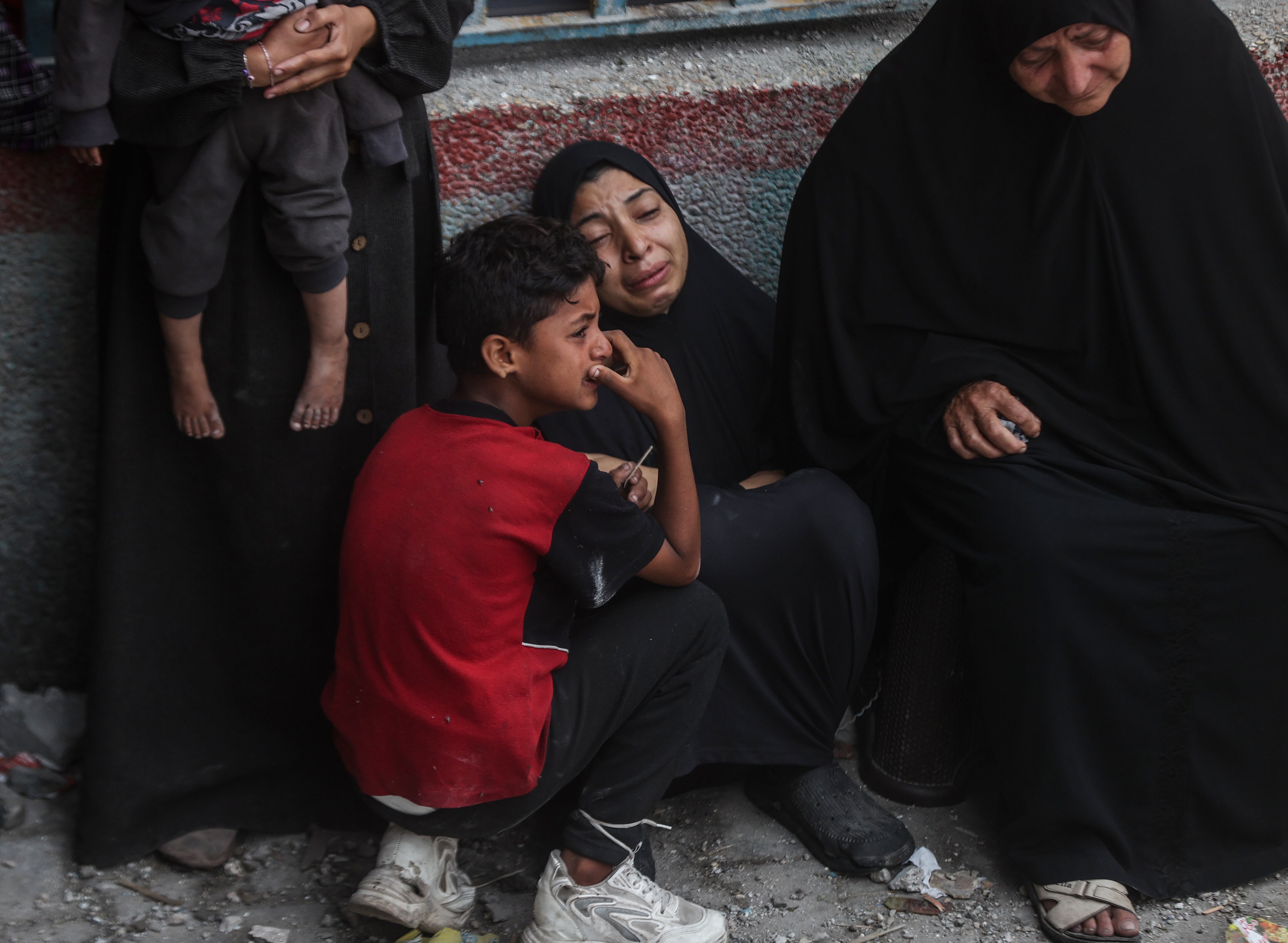 Varios palestinos lloran cerca de la escuela de la UNRWA, que alberga a miles de personas, tras el ataque israelí. El ejército ha asegurado que el ataque aéreo tenía como objetivo tres habitaciones en las que se encontraban entre 20 y 30 milicianos de Hamás, algunos de los cuales participaron en el atentado del 7 de octubre.