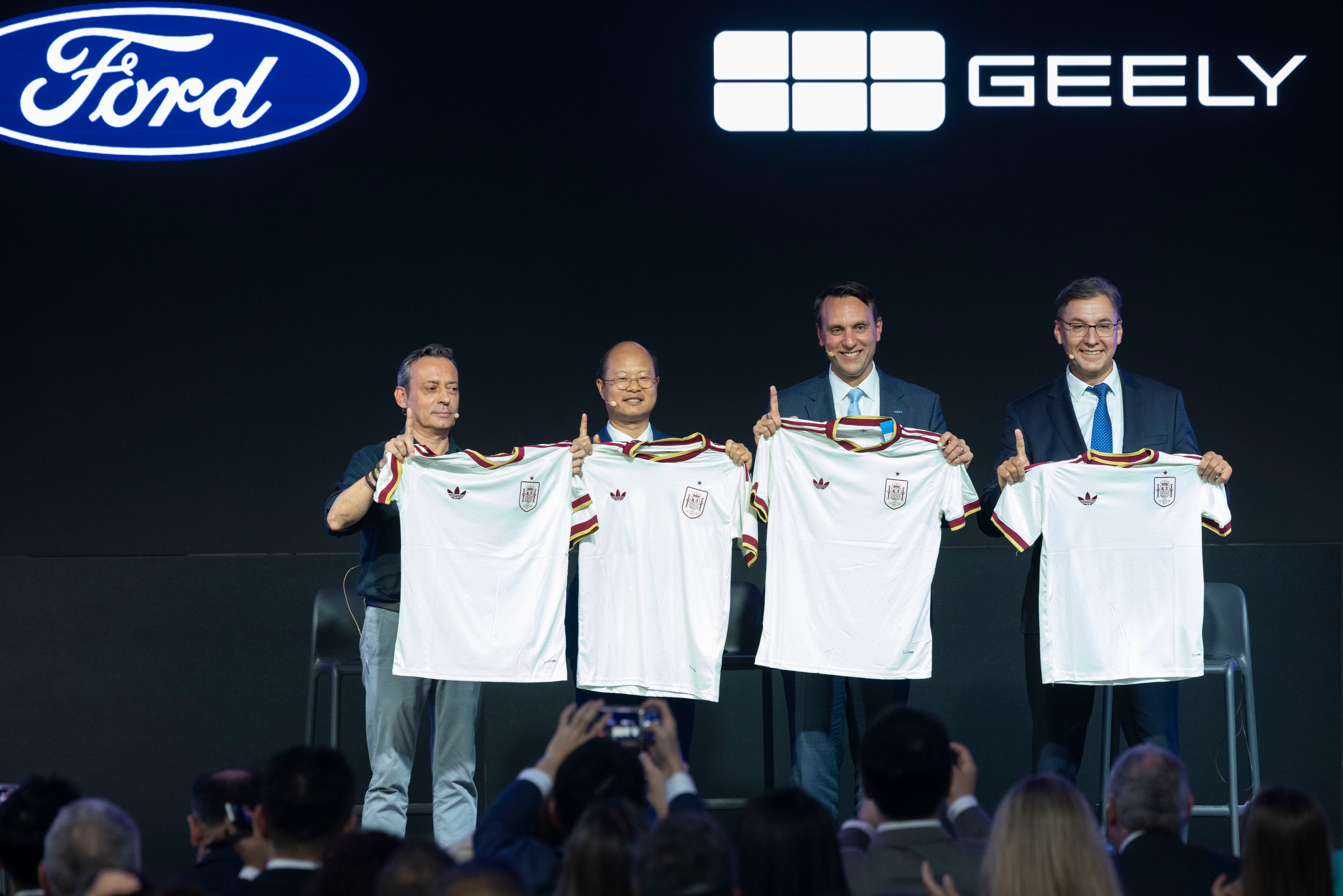 Los dirigentes de Geely y Ford muestra camisetas de la selecicón española, en un guiño a la campeona del mudo.