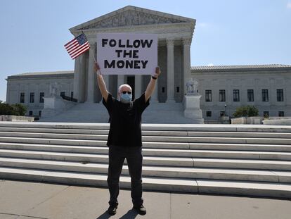 Manifestante diante da Suprema Corte com um cartaz em referência ao caso das finanças de Donald Trump,  na quarta-feira.