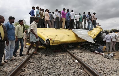 Hombres indios subidos en los restos del autobús escolar que chocó contra un tren en el distrito de Medak, en el estado de Telangana. 24 de julio de 2014.