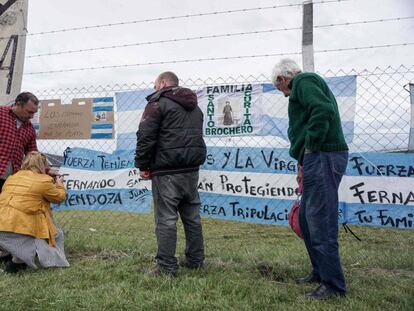 Juan Carlos Mendoza (d) y Carlos Mendoza (i) padre y hermano del submarinista Ariel Fernando Mendoza cuelgan una bandera argentina frente a la Base Naval de Mar del Plata.