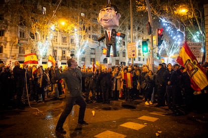 Un hombre se dispone a golpear una piñata que representa a Pedro Sánchez, cerca de la sede del PSOE en Madrid, esta Nochevieja.