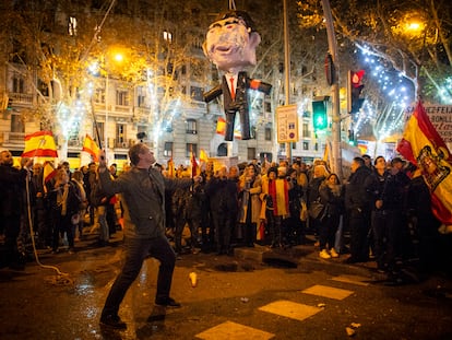 Un hombre se dispone a golpear una piñata que representa a Pedro Sánchez, cerca de la sede del PSOE en Madrid, esta Nochevieja.