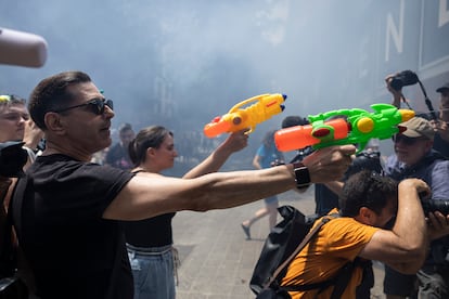 Manifestantes usan pistolas de agua contra turistas que observan la manifestación desde el interior de un hotel.