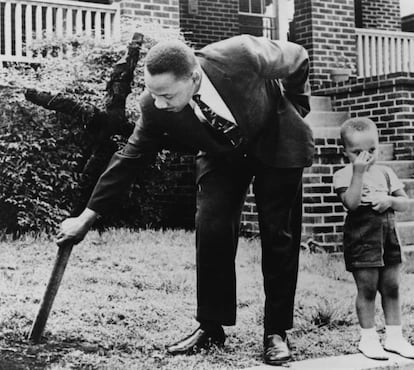 Martin Luther King quita una cruz quemada del KKK del jardín de su casa junto a su hijo en Atlanta, Georgia, el 27 de abril de 1960.