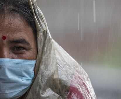 Una mujer se cubre con un plástico durante la lluvia del monzón en Katmandú (Nepal).