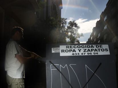 Un hombre deposita una bolsa en un contenedor de ropa.