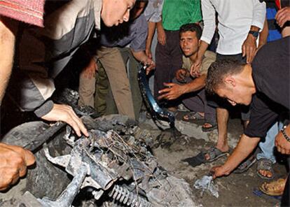 Un grupo de palestinos recoge los restos de la moto calcinada tras el ataque.