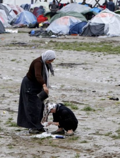 Una mujer ayuda a otra a lavarse el pelo en el campo de refugiados de Idomeni.