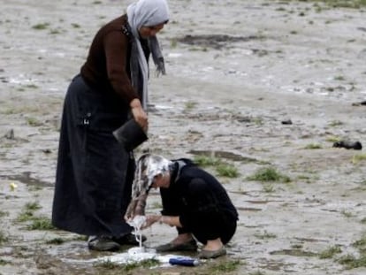 Una mujer ayuda a otra a lavarse el pelo en el campo de refugiados de Idomeni.