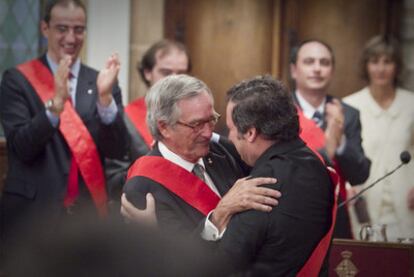 El nuevo alcalde de Barcelona, Xavier Trias, abraza a su antecesor, Jordi Hereu, durante la ceremonia de constitución del Ayuntamiento.