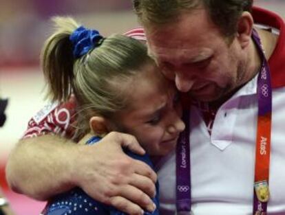 Komova consolada por su entrenador tras perder la final individual