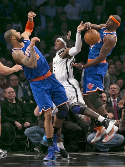 El pívot de los Knicks, Tyson Chandler, y el alero, Ronnie Brewer, intentan quitarle el balón a Gerald Wallace,de los Nets.