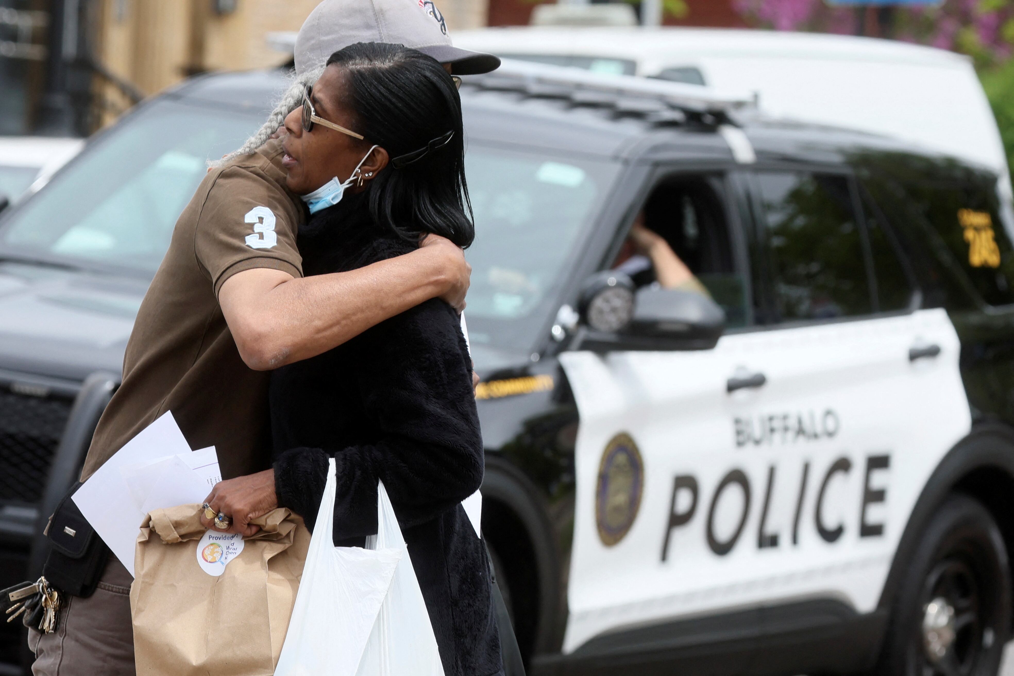 Un hombre abraza a una mujer cerca de la escena de un tiroteo en un supermercado Tops en Búfalo, Nueva York, el 18 de mayo de 2022. 
