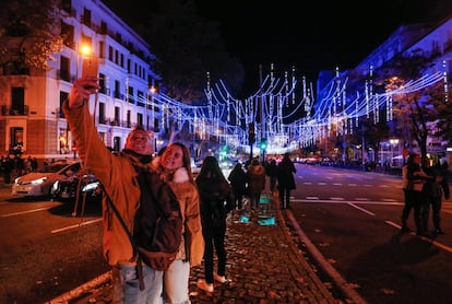 Una pareja se hace una foto con el alumbrado de la Calle Alcalá. 