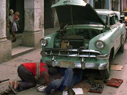 Dos cubanos reparan su coche en una calle de La Habana en 1999.