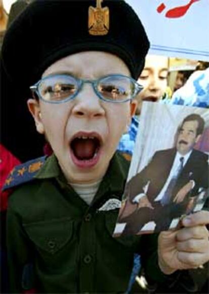 Un niño iraquí vestido de uniforme militar muestra una foto del presidente Sadam Husein, ayer, en Bagdad.