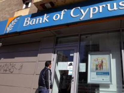 Una viandante lee el comunicado hecho público por la entidad y colocado una sucursal cerrada del Banco de Chipre en el centro de Bucarest (Rumanía). EFE/Archivo