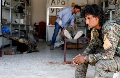 Un soldado de las Fuerzas Sirias Democráticas (SDF) espera sentado mientras atienden a un compañero herido por un francotirador del Estado Islámico en Raqa (Siria), el 28 de junio de 2017.