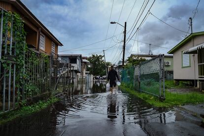 Al menos 10 circuitos eléctricos de la isla quedaron fuera de servicio, dejando a miles de personas sin electricidad, aunque las autoridades aún no determinan el número de afectados por los cortes. En la imagen, un hombre camina a través de un camino inundado en el barrio de Juana Matos, en Catano, tras el paso del ciclón.