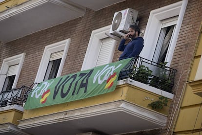 A man on a balcony in Seville with a Vox banner.