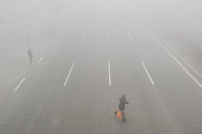 Las autoridades de la localidad de Tianjin han cancelado decenas de vuelos por segundo día consecutivo tras registrar altos niveles de polución en la zona. En la imagen, varios peatones cruzan una calle en Tianjin (China).