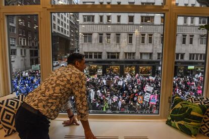 Un hombre mira por la ventana para ver el paso de la Marcha de Mujeres en la ciudad de Nueva York.