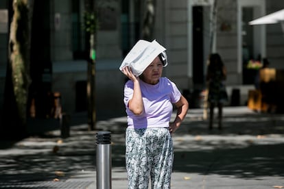 Una mujer utiliza la sombra de su bolso para refugiarse del calor.