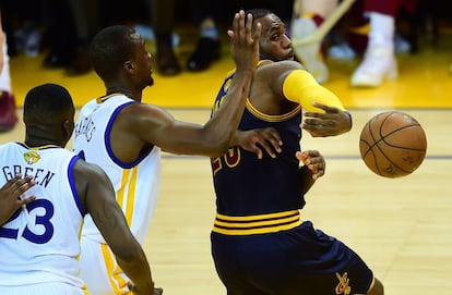 LeBron James en un pase atrás bajo la presión de Harrison Barnes y Draymond Green.