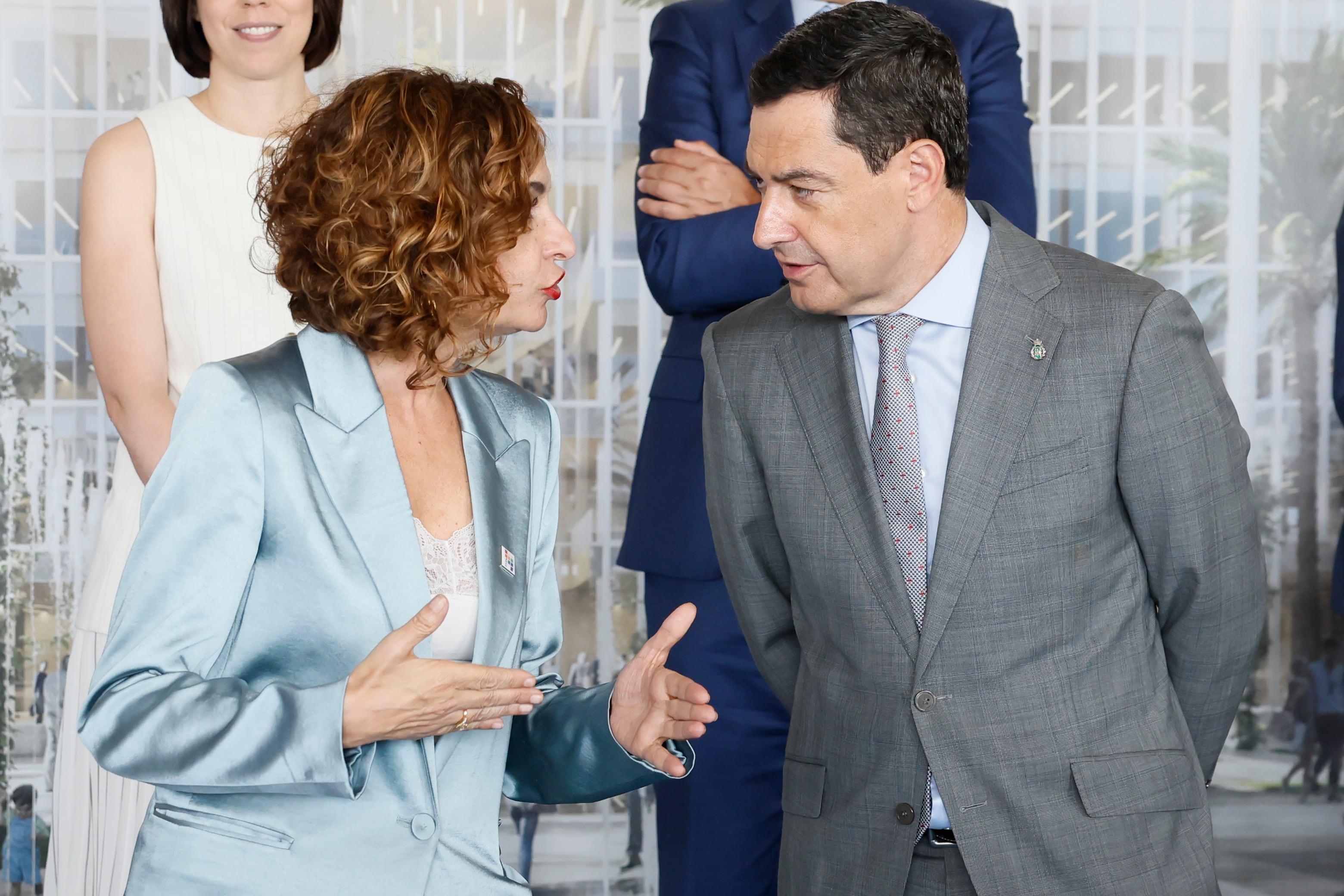 La vicepresidenta primera y ministra de Hacienda, María Jesús Montero, conversa con el presidente de la Junta de Andalucía, Juan Manuel Moreno, en un acto en la isla de la Cartuja de Sevilla el pasado 30 de junio.
