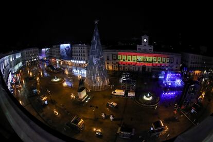 La bandera de España es proyectada sobre la fachada de la sede del gobierno de la Comunidad de Madrid, en la plaza de la Puerta del Sol de Madrid vacía, horas antes de las tradicionales campanadas.