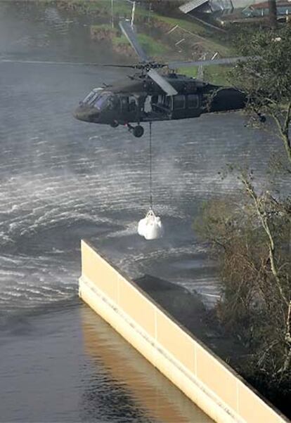 Un helicóptero transporta un saco de arena para reparar un dique.