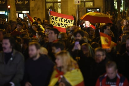 Bandera de España con el lema "Que te vote Txapote" es portada por manifestantes durante la protesta frente a la sede del PSOE.