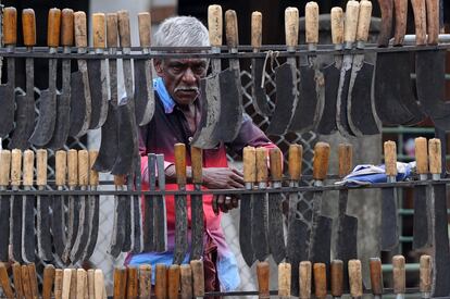 Un vendedor ambulante se asoma entre los cuchillos que vende, en Colombo (Sri Lanka).