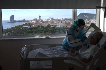 Una asistente de enfermería, alimenta a uno de sus pacientes en la sala covid-19 del Hospital del Mar en Barcelona.