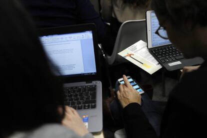 Dos personas trabajan con sus ordenadores y teléfonos móviles, en una imagen de archivo.