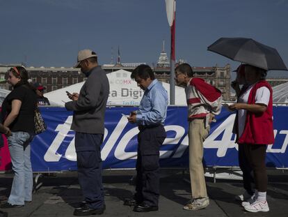 Un grupo de personas mira las pantallas de sus teléfonos móviles mientras hacen fila para entrar a un evento en Ciudad de México.