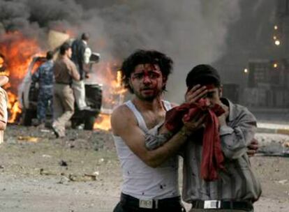 Dos heridos se alejan de un coche bomba dirigido contra un puesto de control ayer en el centro de Bagdad.