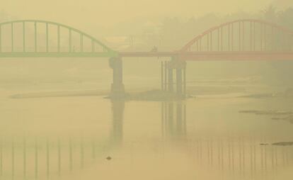 Una motocicleta circula por el puente Betrix bajo una densa capa de niebla causada por el humo de unos incendios en Sarolangun, provincia de Jambi, Indonesia.