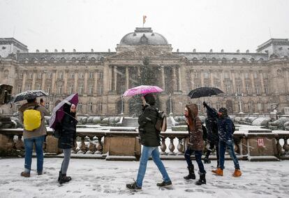 Viandantes se refugian en sus paraguas durante un día de nieve en Bruselas (Bélgica).