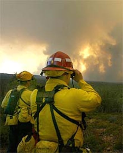 Dos bomberos observan el avance de las llamas hacia el pueblo de Show Low, Arizona.