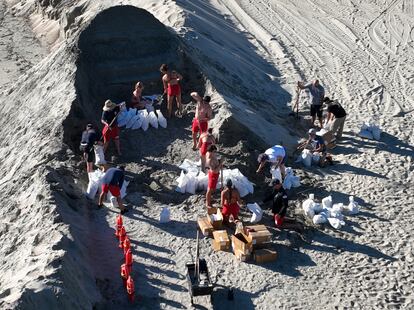 Socorristas apoyan en la construcción de la berma de arena en Long Beach, California. 
