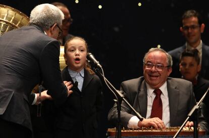 Un funcionario de Apuestas y Loterías del Estado se dirige a Aya, una de los niños de San Ildefonso, durante el sorteo extraordinario de Lotería de Navidad de este viernes.