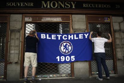 Aficionados del Chelsea colocan una bandera en entre las rejas de una tienda en la Plaza Mayor.