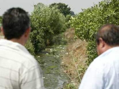 Dos agricultores murcianos contemplan un canal de regadío.