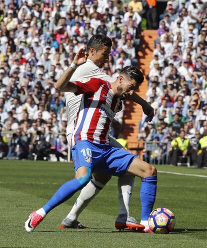 El jugador belga del Atlético de Madrid Yannick Carrasco (delante) disputa un balón con el delantero portugués del Real Madrid Cristiano Ronaldo.